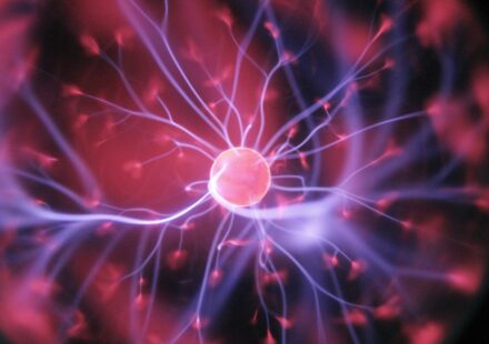 Glowing plasma ball with pink center and electric purple tendrils radiating outward against dark background