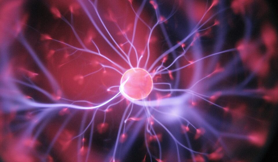 Glowing plasma ball with pink center and electric purple tendrils radiating outward against dark background